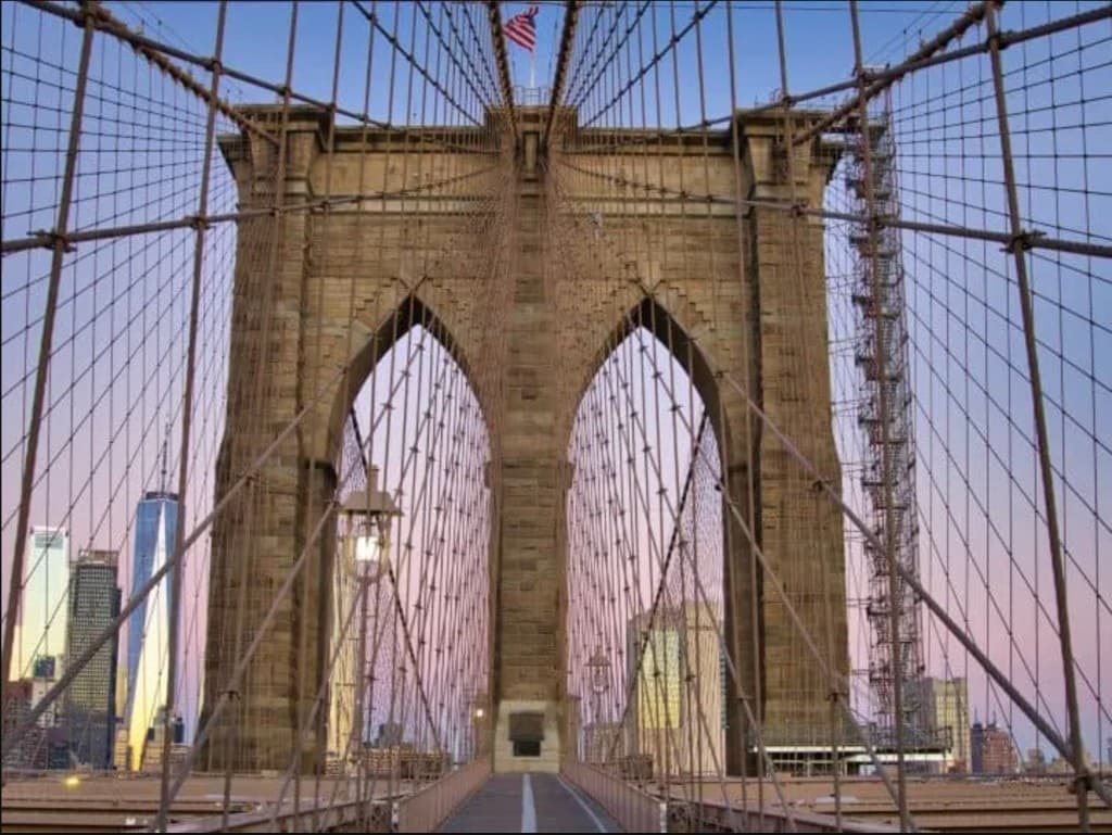 Symmetrical view through a Brooklyn Bridge tower toward the Manhattan skyline