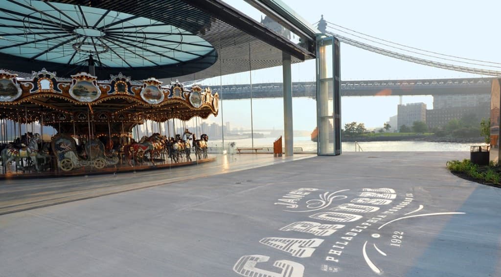 Jane’s Carousel inside its glass pavilion with the Manhattan Bridge behind